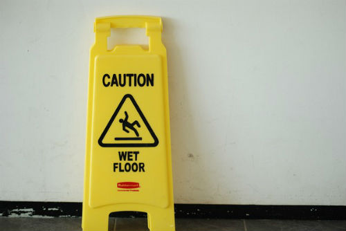 A "Caution, wet floor" sign leabing against a wall