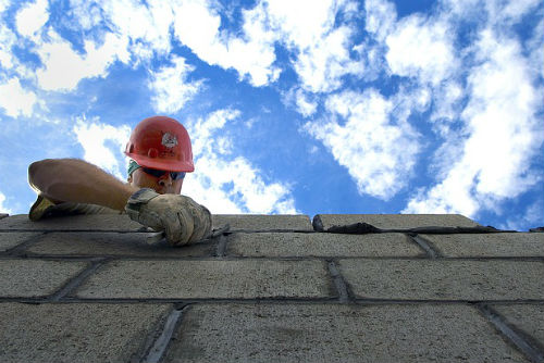 A man in a hardhat laying bricks