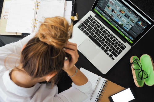 A woman sitting at a computer getting stressed while filing for workers compensation.