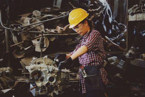 A woman working in a hard hat operating a piece of heavy equipment