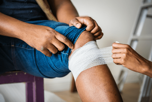 a man getting his knee wrapped in gauze after an injury