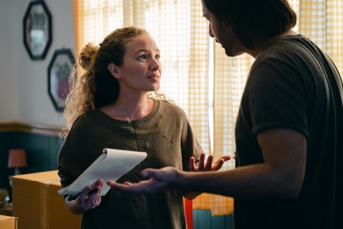 A woman holding a stack of medical bills looking at her husband in a stressed moment.