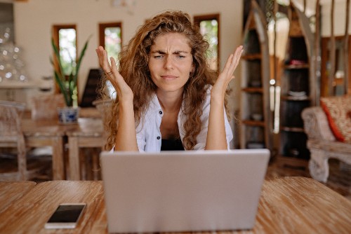 A woman staring at a laptop screen with a frustrated look while trying to file an appeal for workers comp