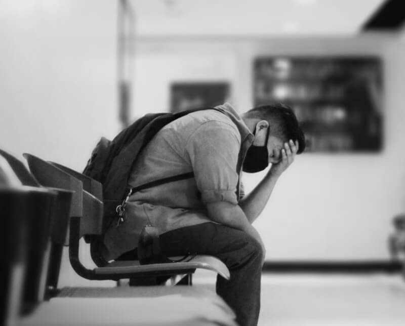 A man sitting in a doctors office chair with his head in his hands