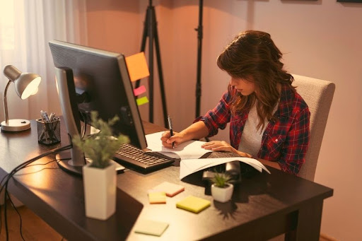 A woman sitting at a desk filling out paperwork to start a workers comp claim
